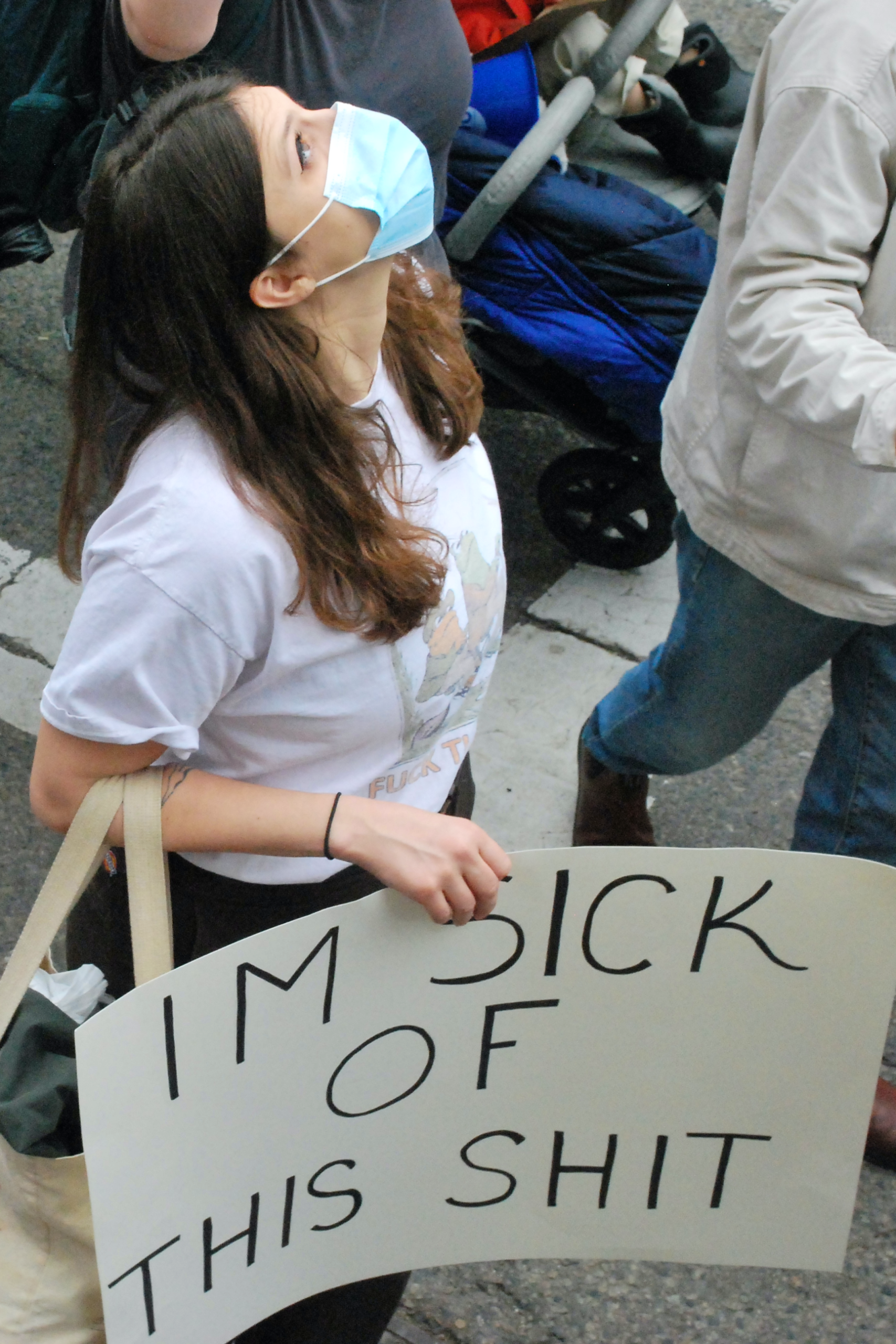 woman with protest sign reading "Sick of this shit" in all caps